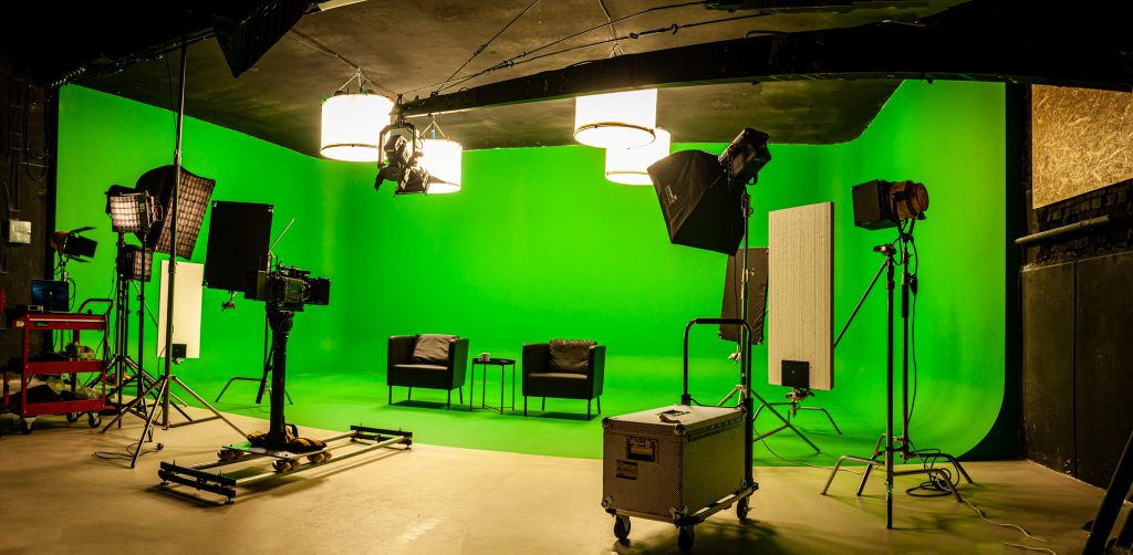 Studio cu fundal verde, lumini și două fotolii pregătite pentru un podcast