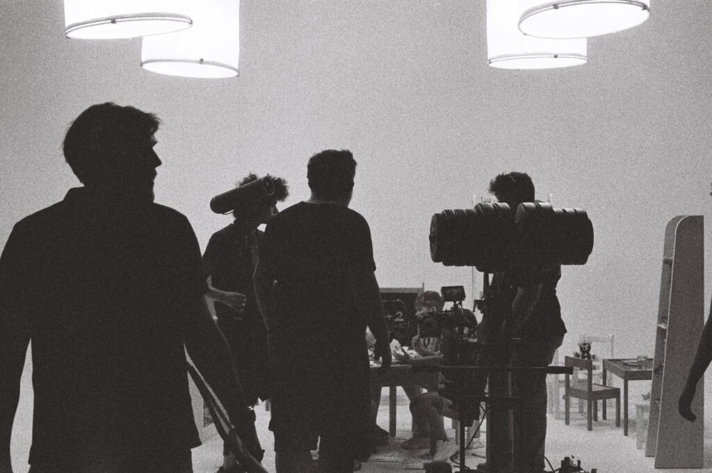 Echipa pe platou, în contralumină, pregătind o filmare în studio